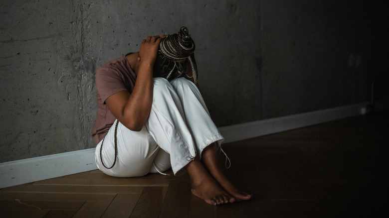 Başı bir duvara karşı oturan kadın