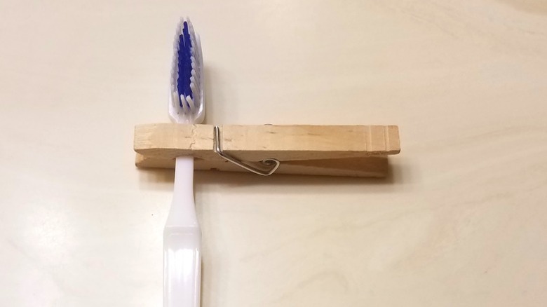 Ahşap dolap kapısı üzerinde diş fırçası tutan ahşap clothespin