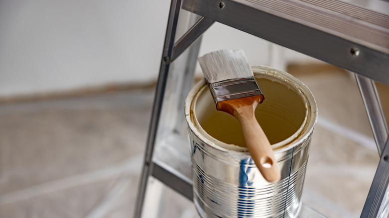 Bir merdiven üzerine açık renkli boya teneke üzerine yerleştirilen boya fırçası