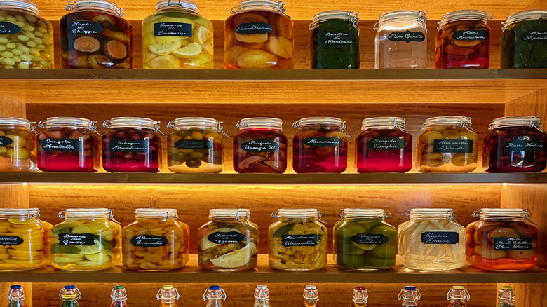 Güzel olarak etiketlenmiş konserve yiyecekler aydınlatılmış kiler raflarında oturuyor