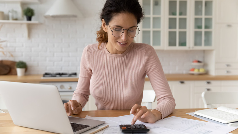 Mortgage maliyetlerini belirlemek için hesap makinesi kullanan kadın