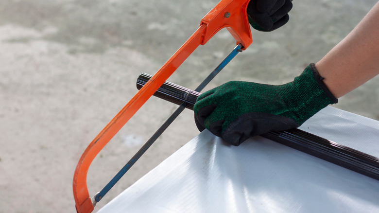 Siyah eldiven giyen eller, bir hack pisti ile siyah bir boru kesti