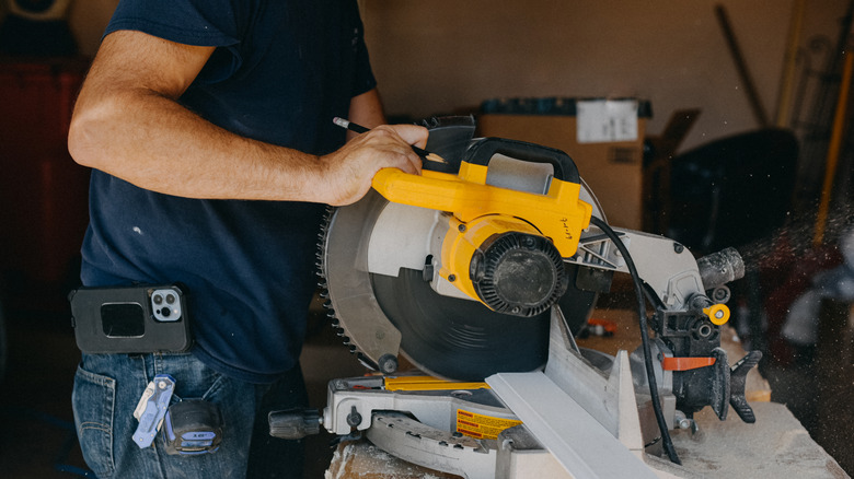 Sarı elektrikli testere kullanarak mavi gömlekli bir kişi