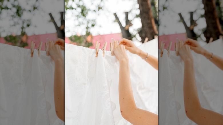 Bir hatta kurumaya perdeleri asan bir kişi