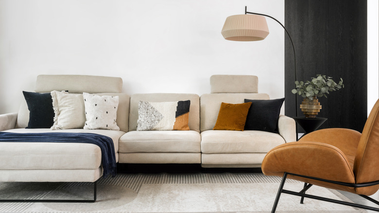 Kesit kanepe, çağdaş lamba ve peluş sandalyeli modern bir oturma odası