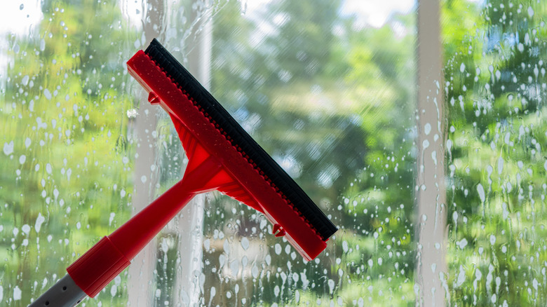 Kir ve enkazları çıkarmak için pencereleri temizleyen kişi