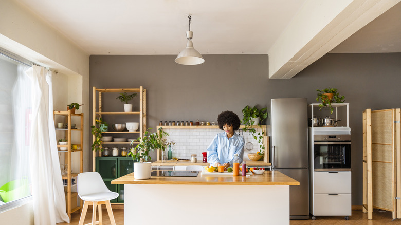 Bir kadın, yukarıda asılı tek bir kolye ışığı ile bir mutfak adasında biber keser