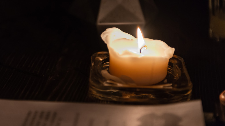 Bir kül tablasında mum yakıyor