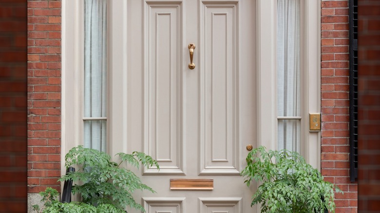 Bir ön kapının dış görünümü, ön kapının her iki tarafındaki iki pencerenin içinde perdeler gösterir