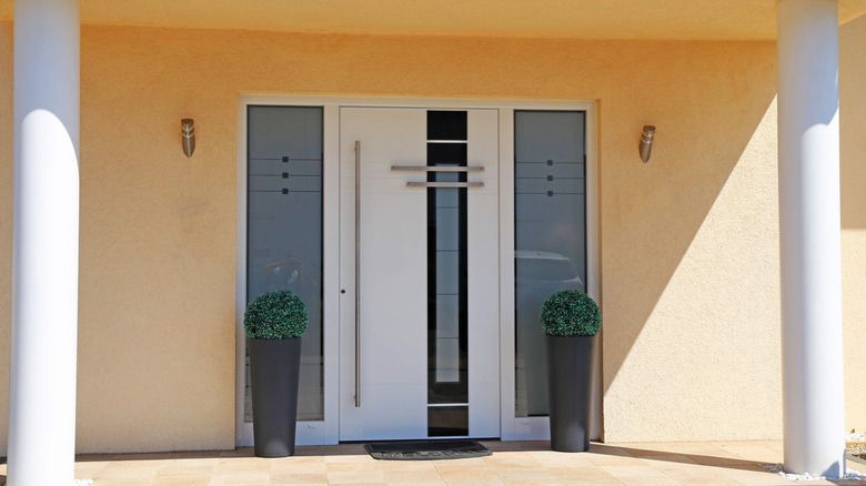 Modern bir ön kapı, küçük bir çizgi ve geometrik tasarıma sahip buzlu cam kenarlara sahiptir