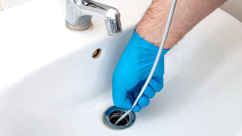 lavabo tahliyesinde sıhhi tesisat yılanı kullanan kişi