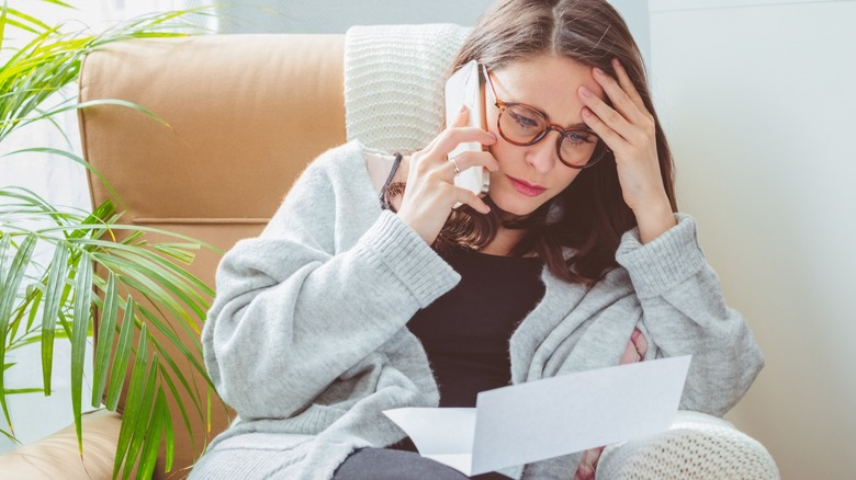 Telefonda mutsuz kadın kağıda bakıyor