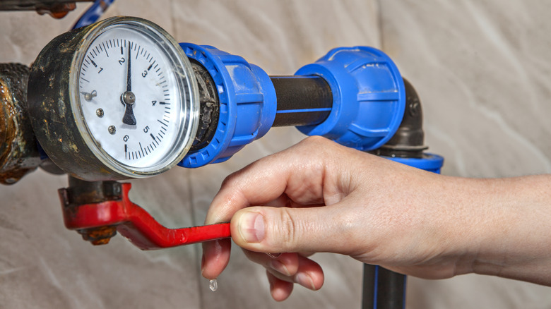 Kırmızı su valfini çeviren bir el