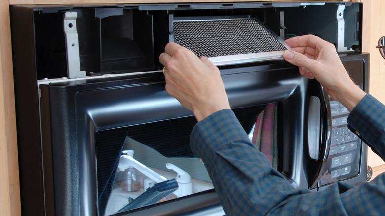 Mikrodalganın gres filtresini kaldıran iki el