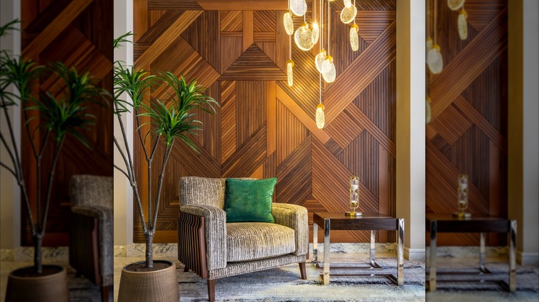 Modern bir bej koltuk ve yan masanın üzerinde sarkan bir avize asılı