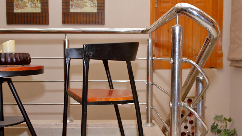 Paslanmaz çelik merdiven rayının yanındaki küçük bir metal masa ve sandalye.