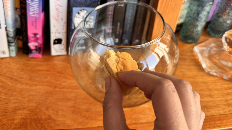 Bir el ekmeği bir cam vazonun yüzeyine basan bir el.