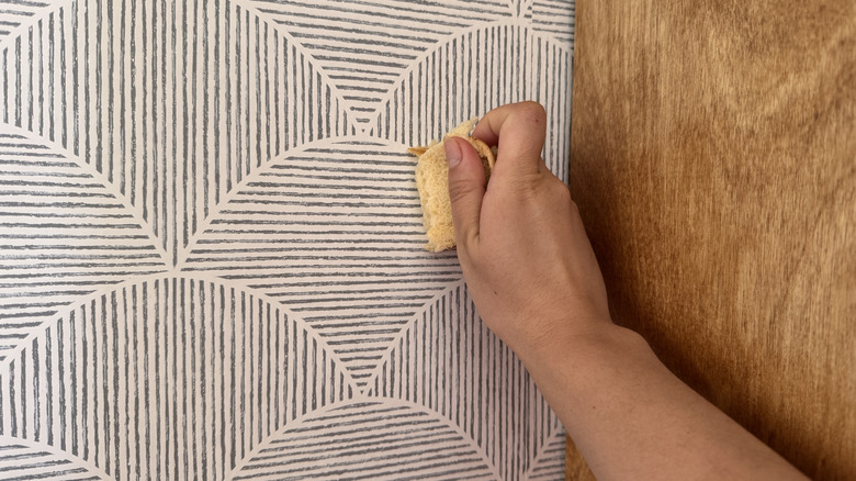 Bir parça ekmek parçasını temizlemek için duvar kağıdına bastırıyor.