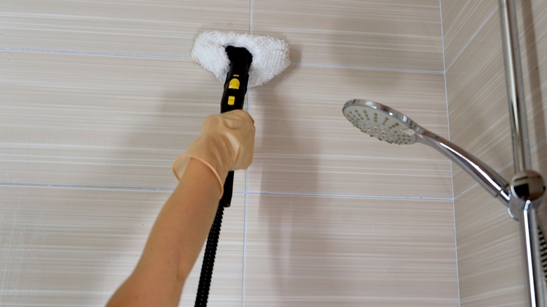 Bir buhar temizleyicisini kullanan bir kişinin çekimini kapatın