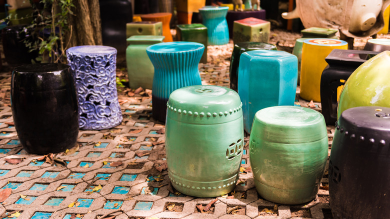 Bir çeşit renkte seramik bahçe tabureleri bir döküntü verandasında oturur