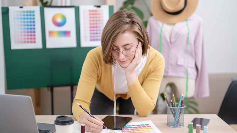 Renk grafiği ile çalışan bir masanın üzerine eğilen sarı bir hırka giyen kadın