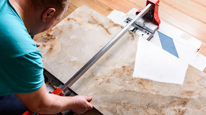 Büyük bir taş kiremit parçası üzerinde karo kesici kullanan adam