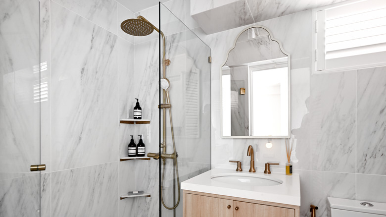 Şık bir mermer duşa üç köşe rafı monte edilmiştir