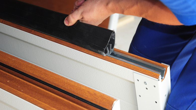 Garaj kapısına alt hava koşullarına dayanıklı mührü takan adam