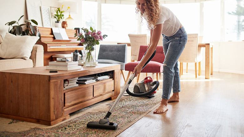 Oturma odasında bir halı vakumlayan bir kadın
