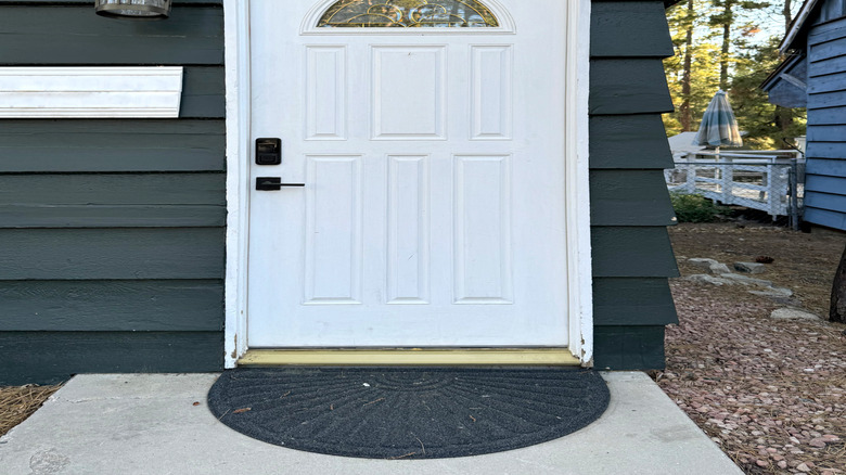 Karanlık bir evde yuvarlak pencereli beyaz bir kapı vardır.