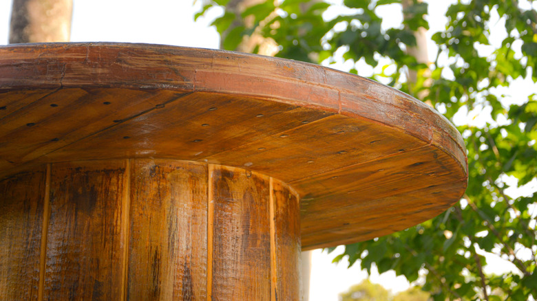 Arka planda ağaç ile rustik görünümlü bir kaplama ile ahşap bir makara masası