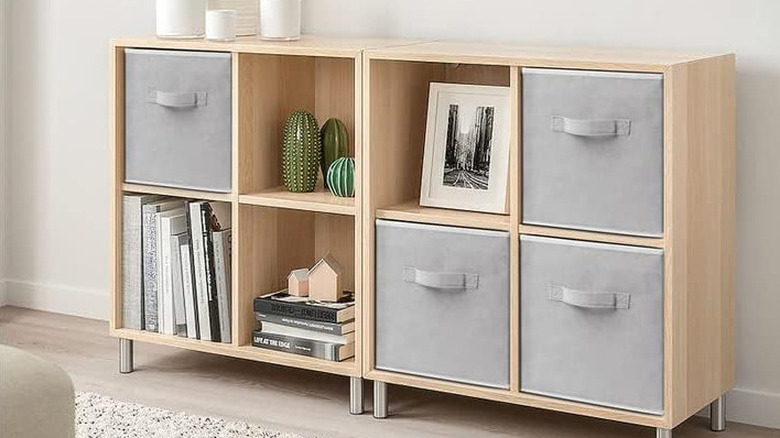 Gri depolama küpleri, kitap yığınları ve sulu meyveli ahşap bir raf.