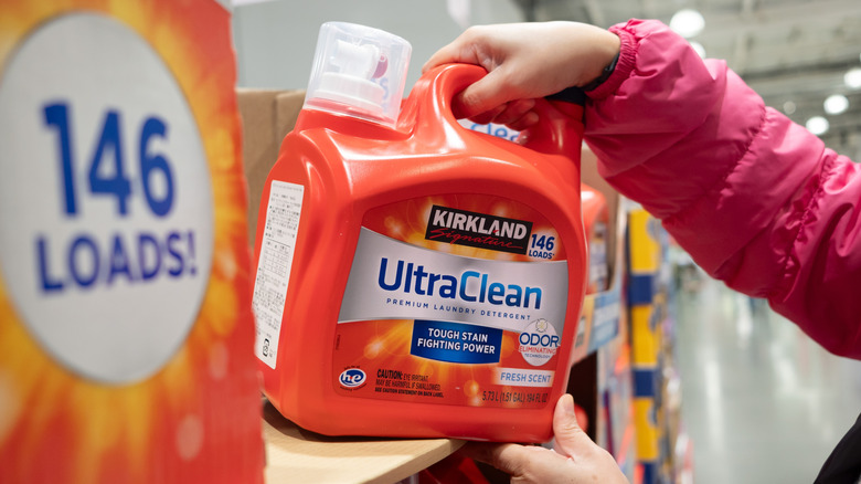 Kadın kolları Kirkland ultra temiz deterjanı raftan alıyor