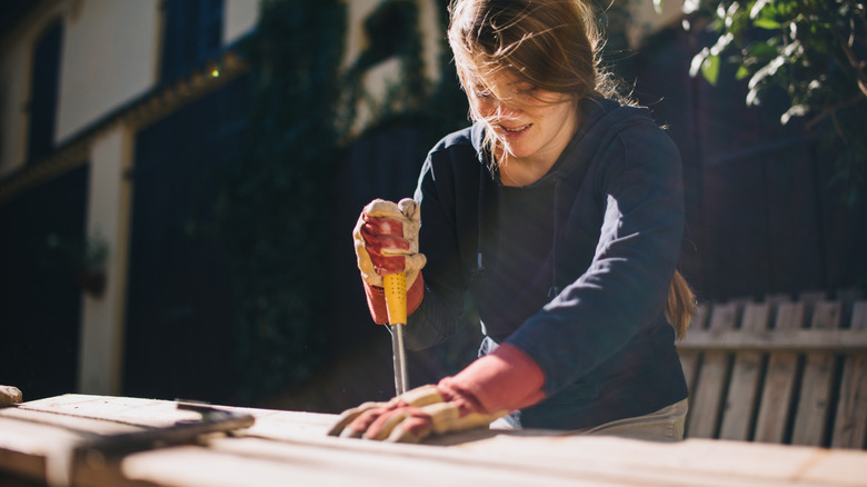 Ahşap parçasında alet kullanan kadın