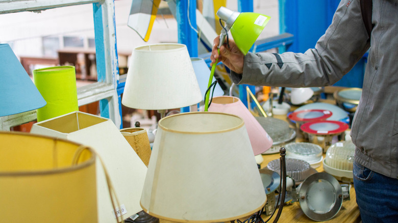 Tasarruflu bir mağazada yeşil masa lambası toplayan kişi