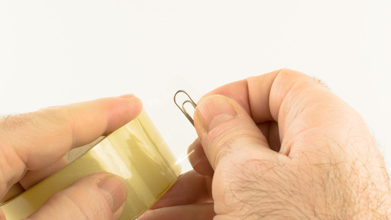 Adam paketleme bandının sonuna bir kağıt klipi koyuyor