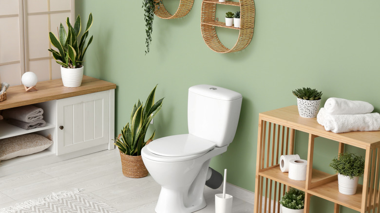 Nane yeşil duvarlarını yumuşatmak için ahşap aksan kullanan banyo