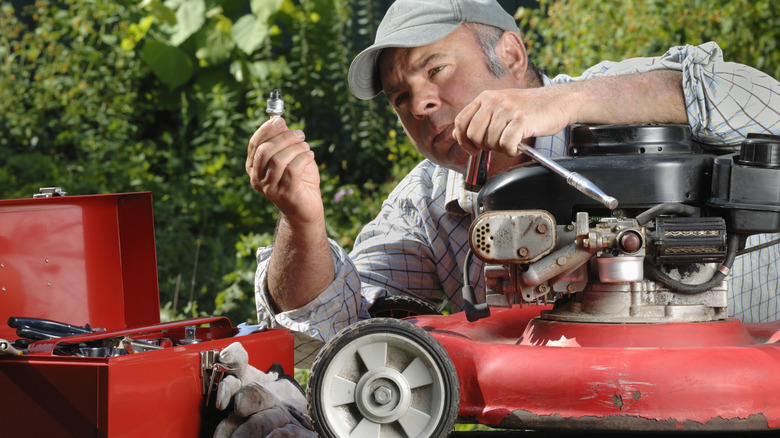Hizmet sağlamak için çim biçme makinesi üzerinde çalışan bir adam