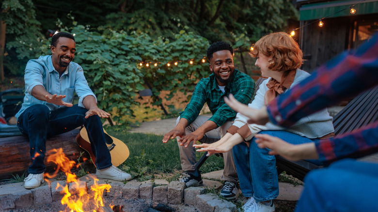 Bir arka bahçe ateş çukuru etrafında oturan arkadaş grubu