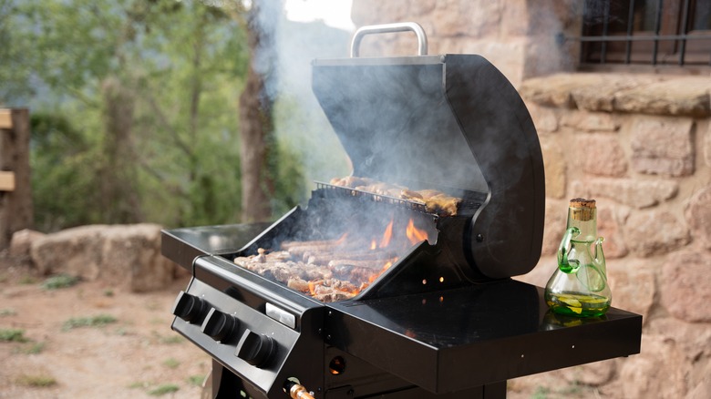 Üzerinde yiyecek pişiren ve havada duman yükselen bir açık ızgara