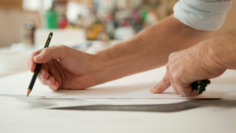 Bir el izleme yapmak için bir kalem kullanırken, diğer el kağıdı tutar.