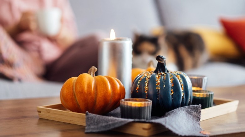 Sehpa üzerinde ahşap tepsi mumları olan küçük kabaklar