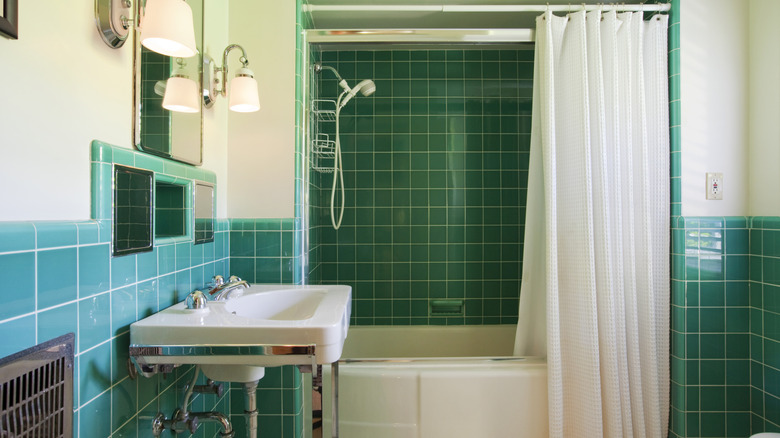 Beyaz duş perdesi ve astar kombo ile deniz mavisi döşenmiş banyo