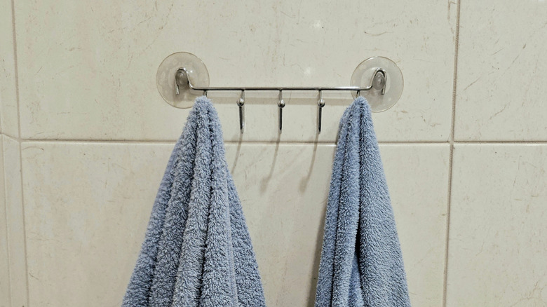 Kiremit duvarında vantuz monte edilmiş raftan asılı havlular