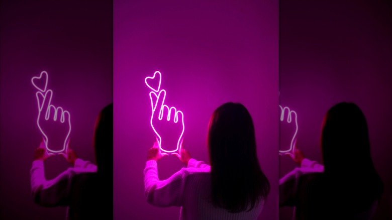 Bir kadın bir duvara neon işareti asıyor