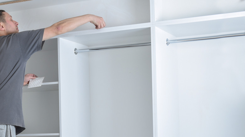 Beyaz dolap sistemini gri gömlek takan adam