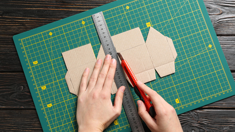 Karton dilimleme sırasında kesme paspası kullanan adam