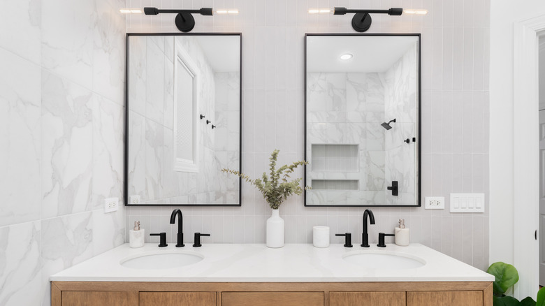 Siyah, kontrastlı çift makyaj muslukları olan parlak beyaz bir banyo