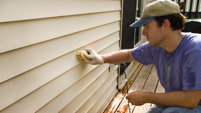 Bir ovma fırçasıyla siding temizleyen adam