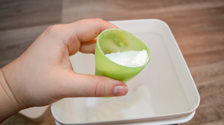 Bir fincan toz çamaşır deterjanı tutan bir el